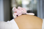 Close up shot of a teddy bear on a pregnant womans stomach --- Image by © 81A Productions/Corbis