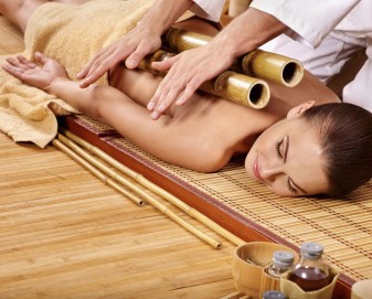 Young woman getting bamboo massage. Male therapist.